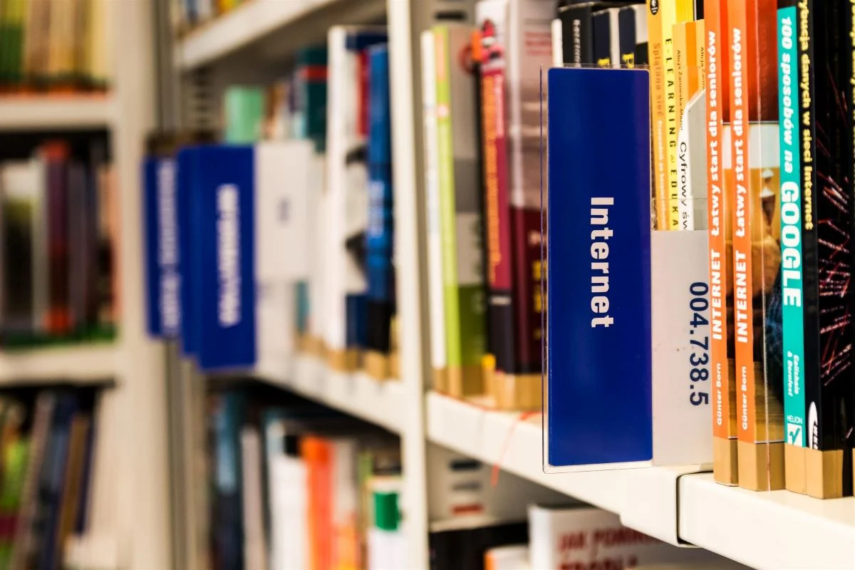Library shelf focused on a book with 'Internet' on the spine among a variety of other books with colorful covers, symbolising the wealth of information available on technology and the internet.
