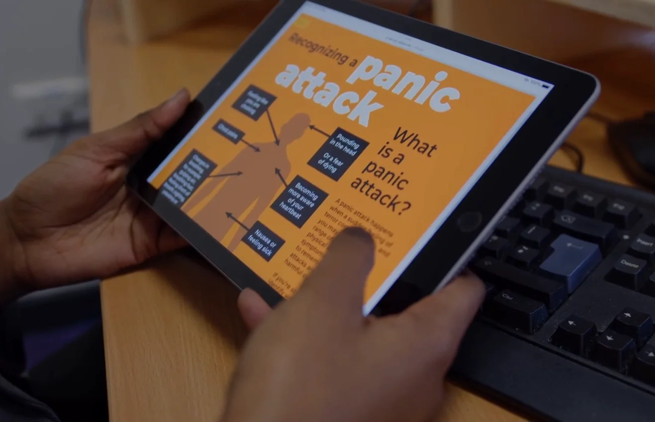 Person holding a tablet displaying an educational graphic about recognizing a panic attack.
